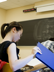 A student in Center Hall, with digital sign in the background.