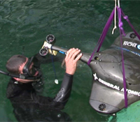 A representative of the Navy helps lower the Stingray into the pool at The Space and Naval Warfare S