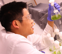 Garfield Kwan inspects a beaker full of algae