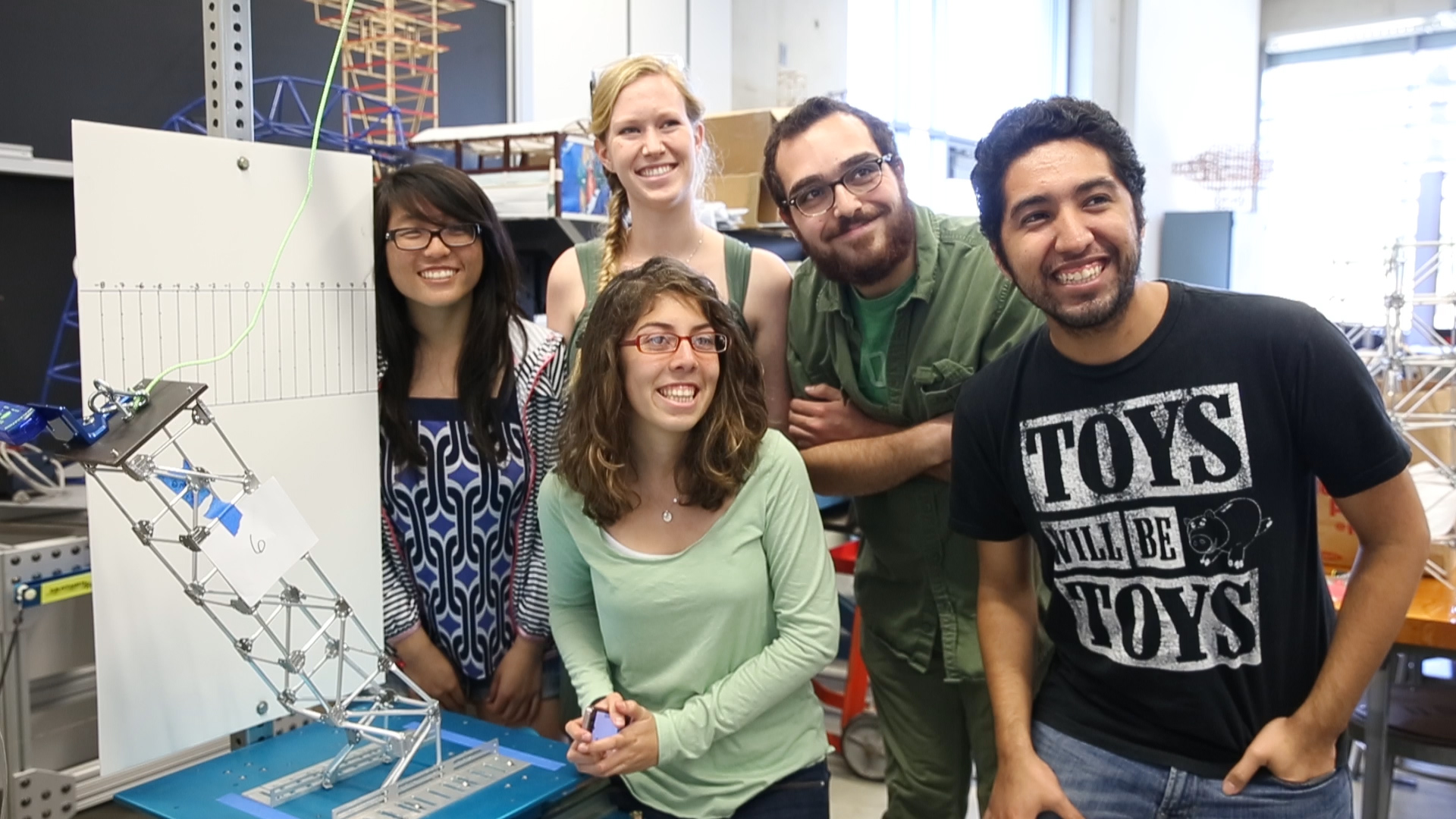 Students pose with the turbine tower they created, which was toppled in a simulated earthquake. 